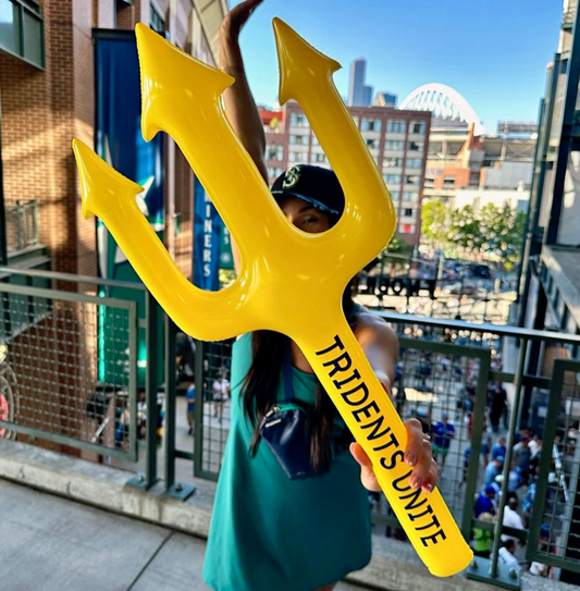 Person holding a large yellow inflatable trident with 'Tridents Unite' text against an urban background. Seattle