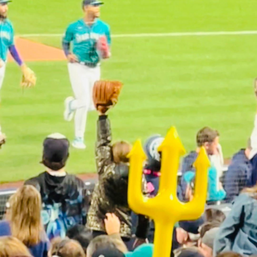 Baseball game in progress with a fan holding a yellow trident-shaped foam finger. Julio Rodrigrez. Julio Trident